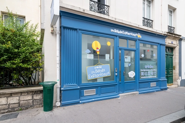 Façade de la crèche Les Bébés Explorateurs de Neuilly-sur-Seine (92200) – devanture bleue avec enseigne, vitrines décorées d'un ballon soleil et logo Les Bébés Explorateurs