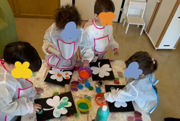 Quatre enfants font de la peinture avec des tabliers de protection en crèche